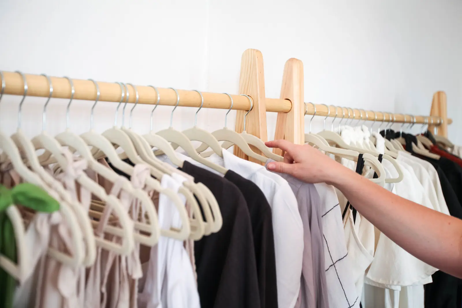 A shopper browsing clothing on a wooden rail