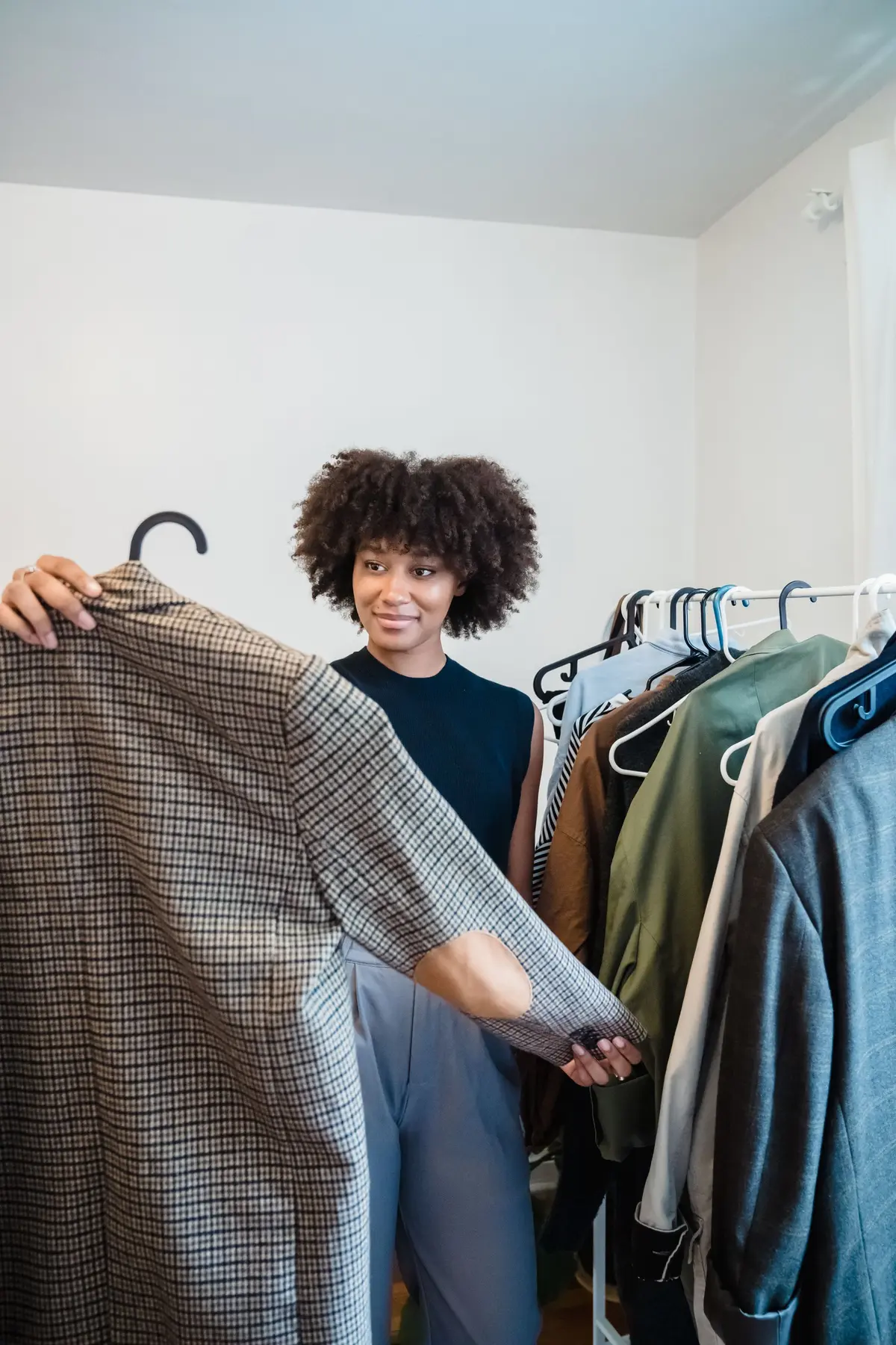 Person thoughtfully choosing clothing from a rail